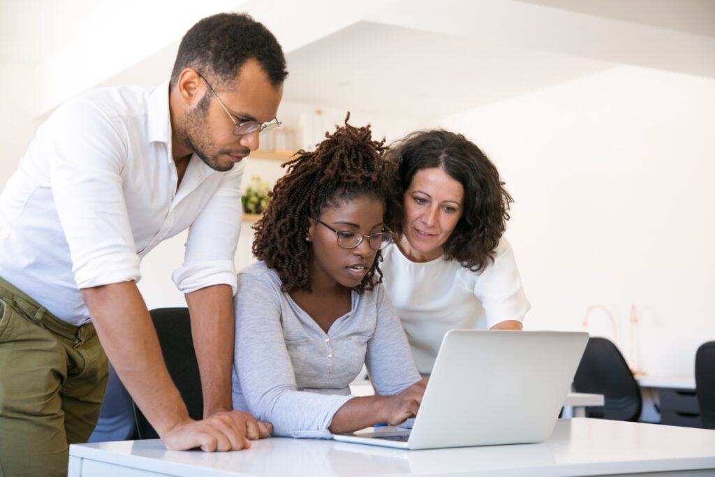 A young business professional looks at a computer as two peers help her to decide on a career